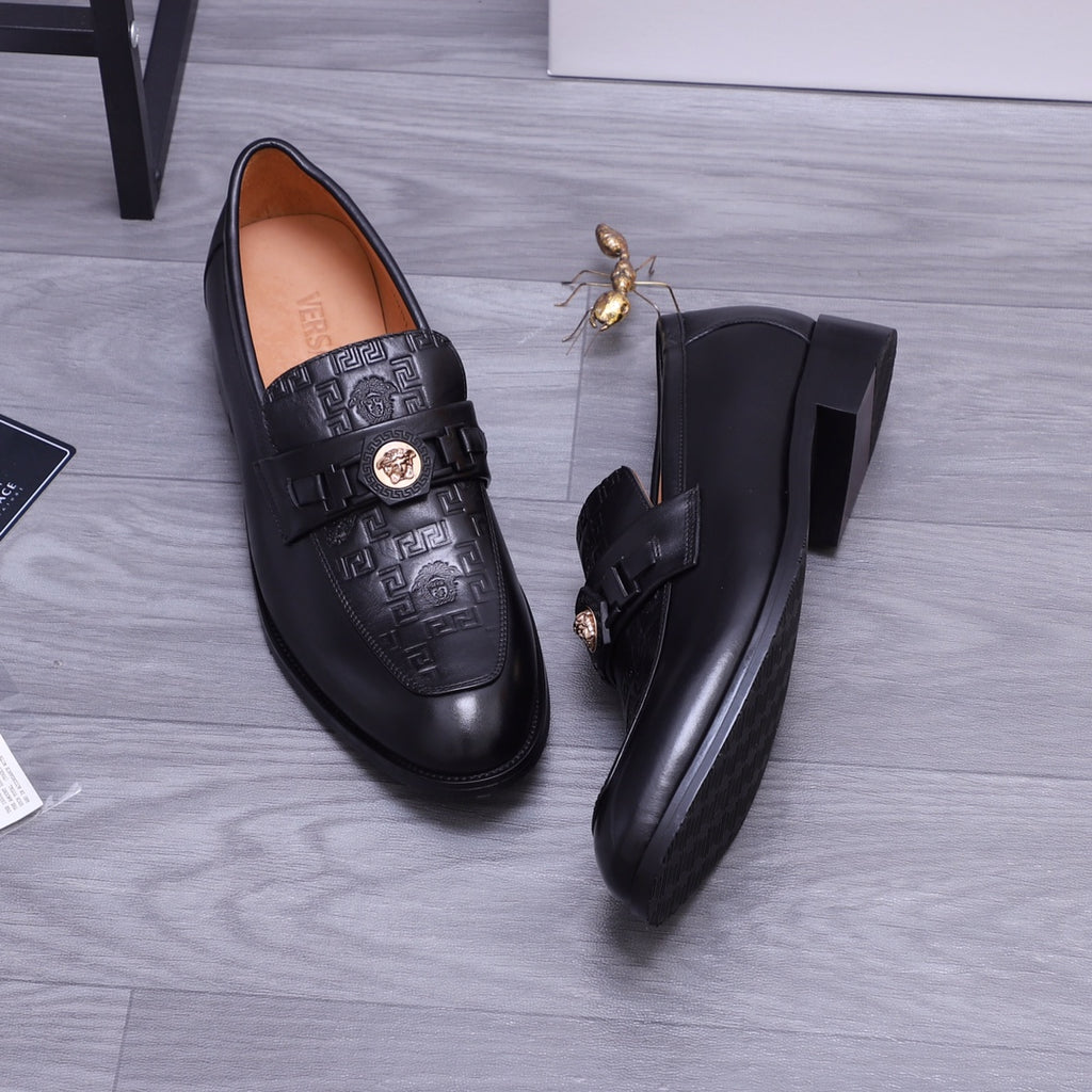 Top view of black Versace loafers with embossed strap and gold crest medallion