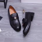 Top view of black Versace loafers with embossed strap and gold crest medallion
