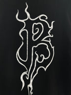 Black T-shirt close-up of white flame monogram print