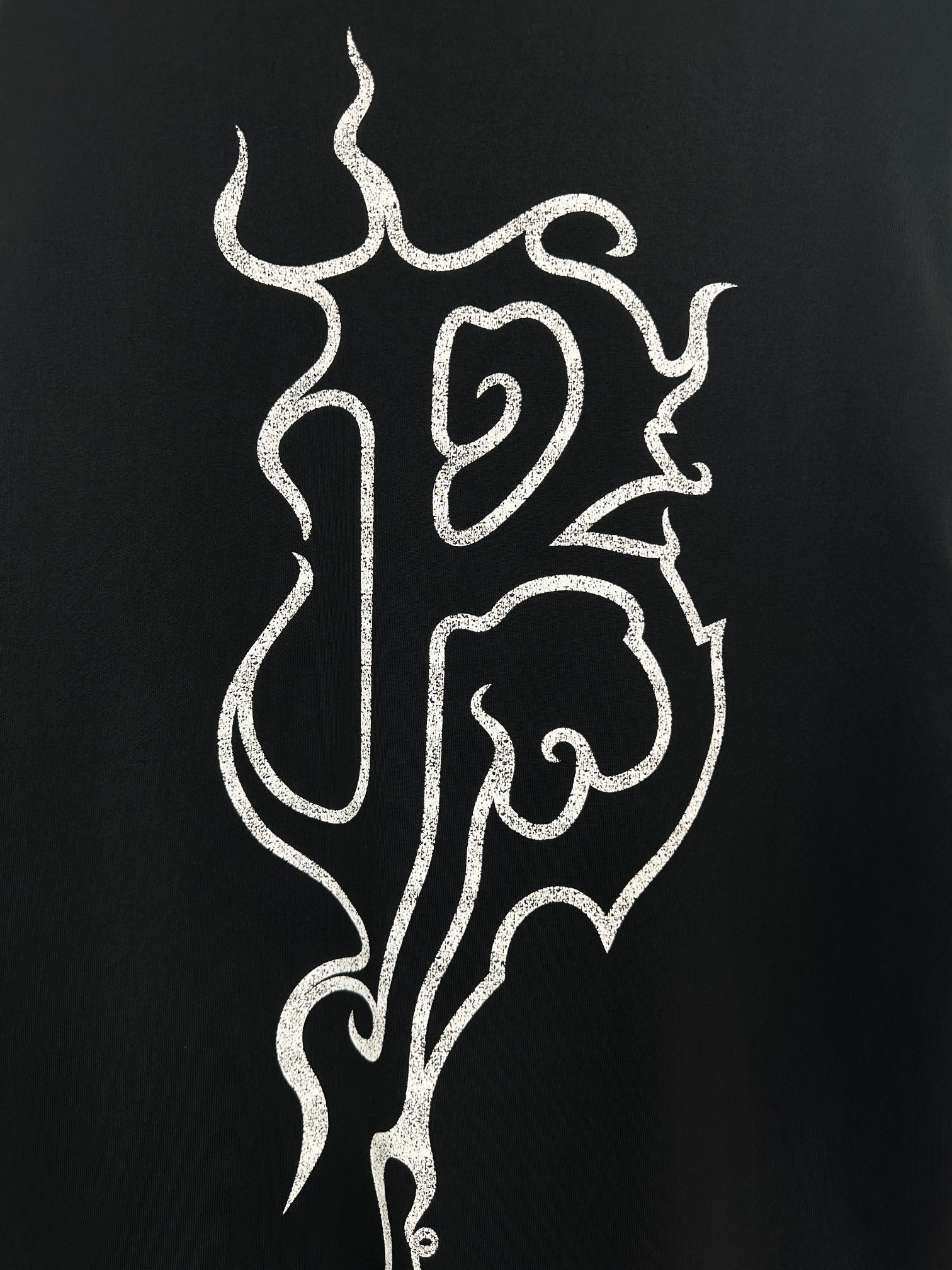 Black T-shirt close-up of white flame monogram print