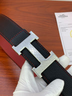 Black leather belt detail: silver H buckle, textured strap, red-stitched edge