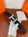 Black textured leather belt with silver-toned H buckle, held by white-gloved hand
