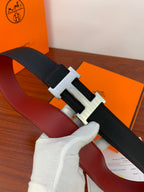 Hermes belt with black leather strap and silver-toned H buckle, laid out