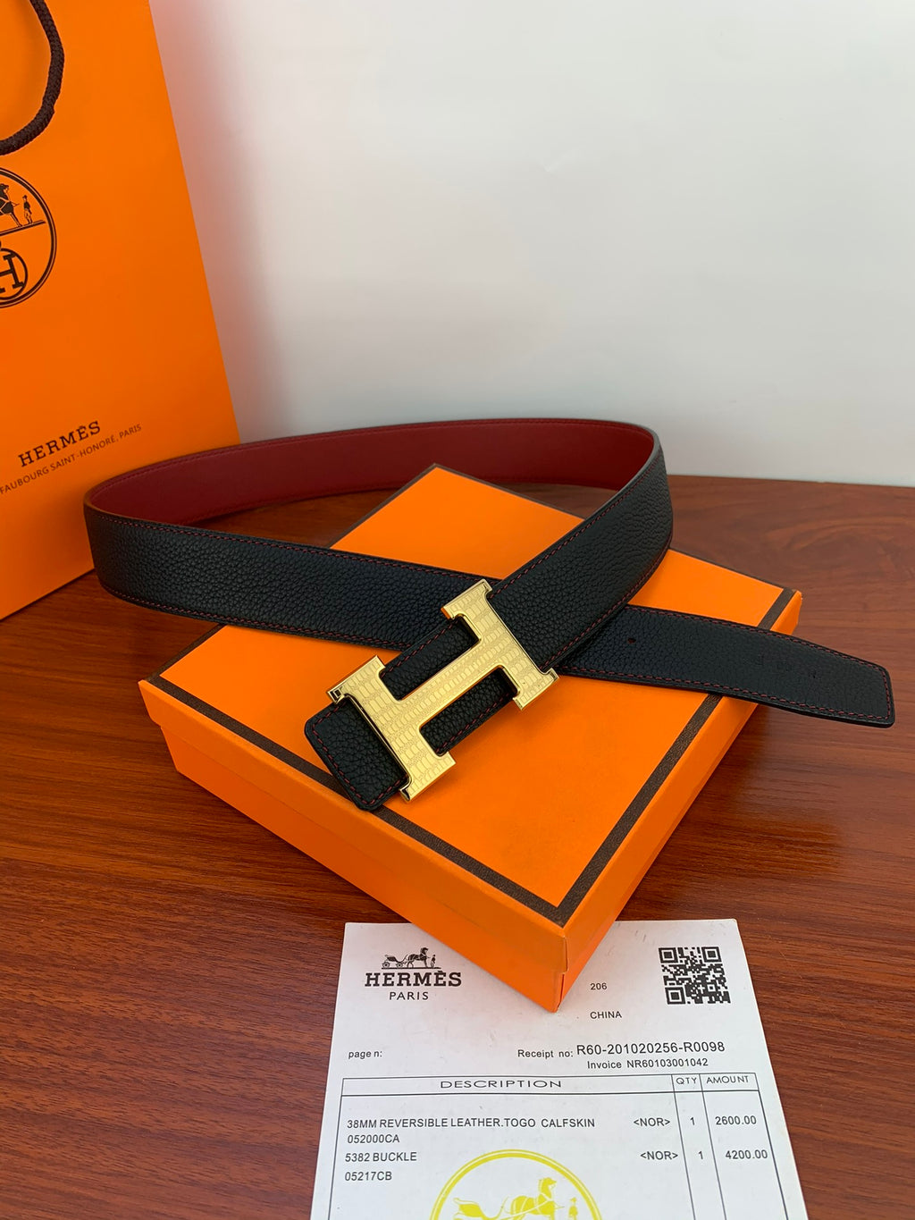 Hermes belt with black leather strap and gold H buckle on a box