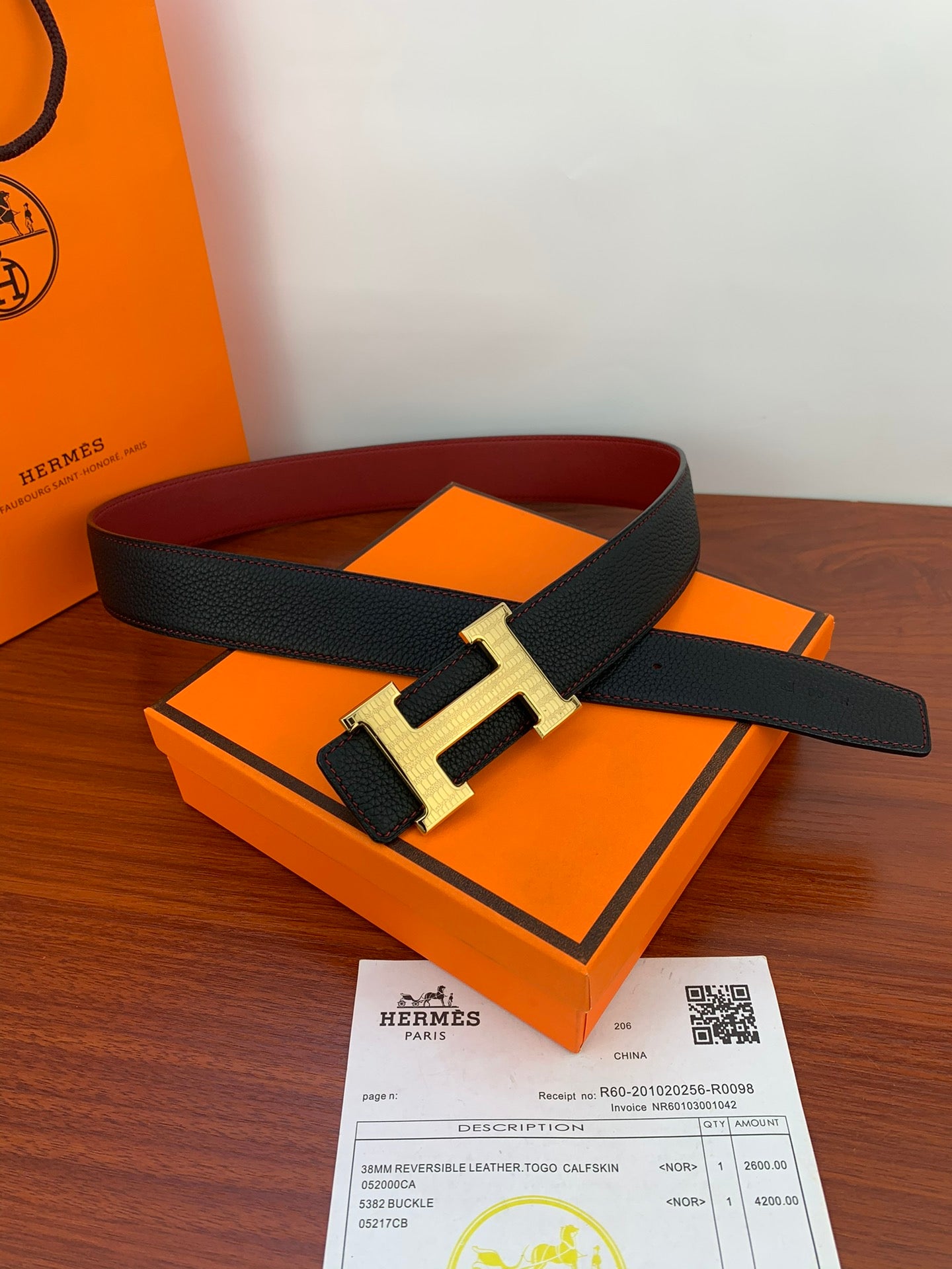 Hermes belt with black leather strap and gold H buckle on a box
