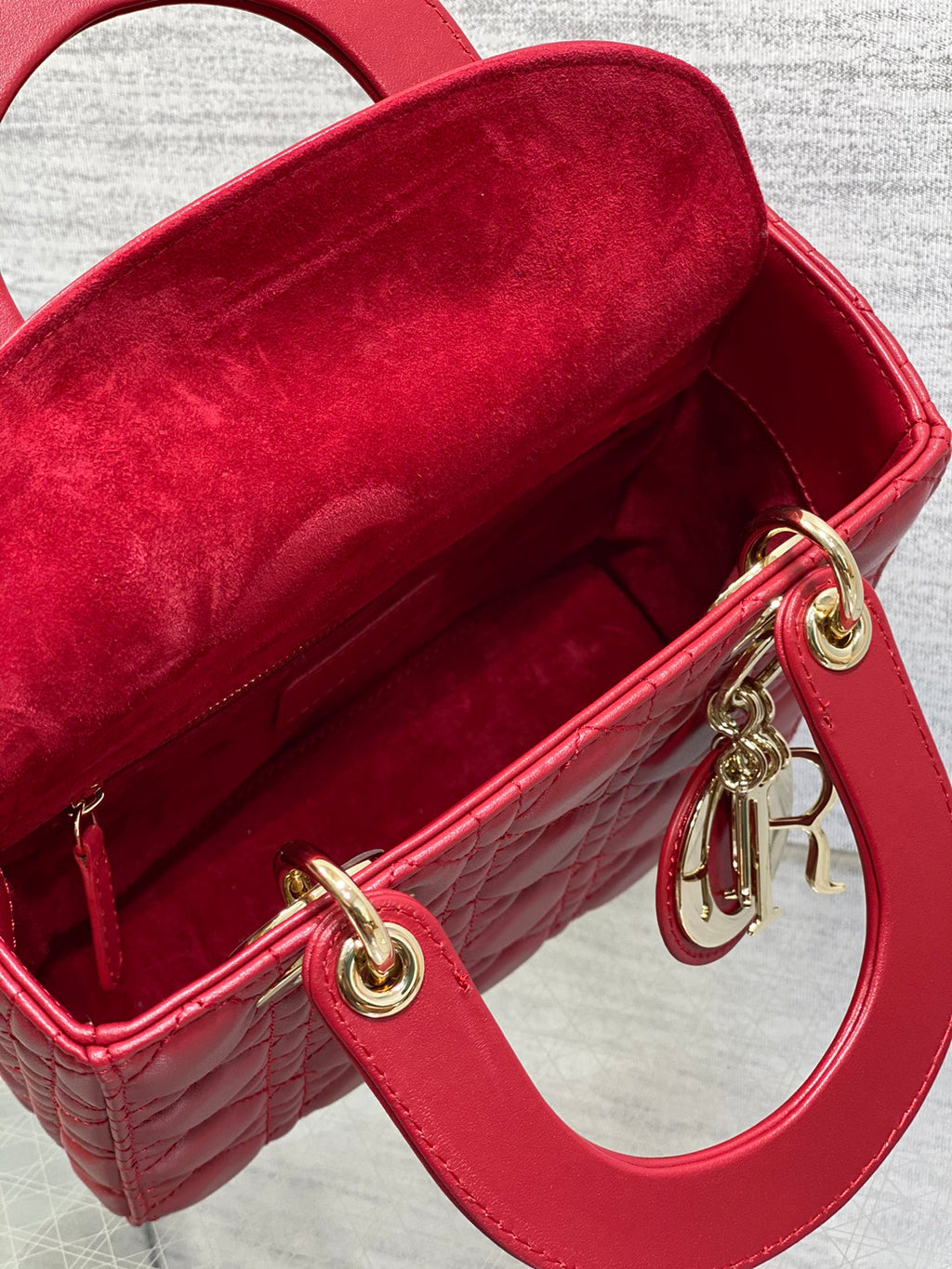 Red Dior handbag interior with red lining and gold hardware rings at the top opening