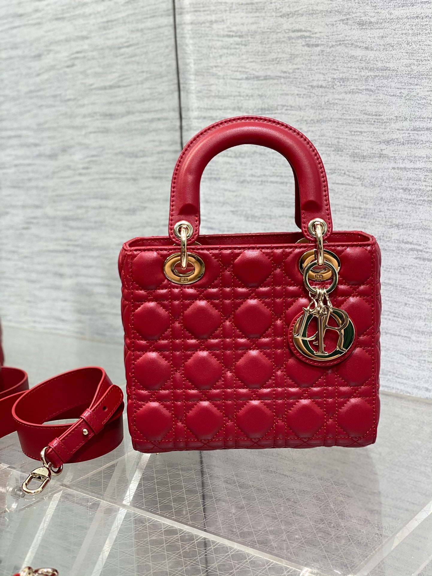 Red quilted Dior handbag with top handles and crossbody strap, gold rings and logo charm