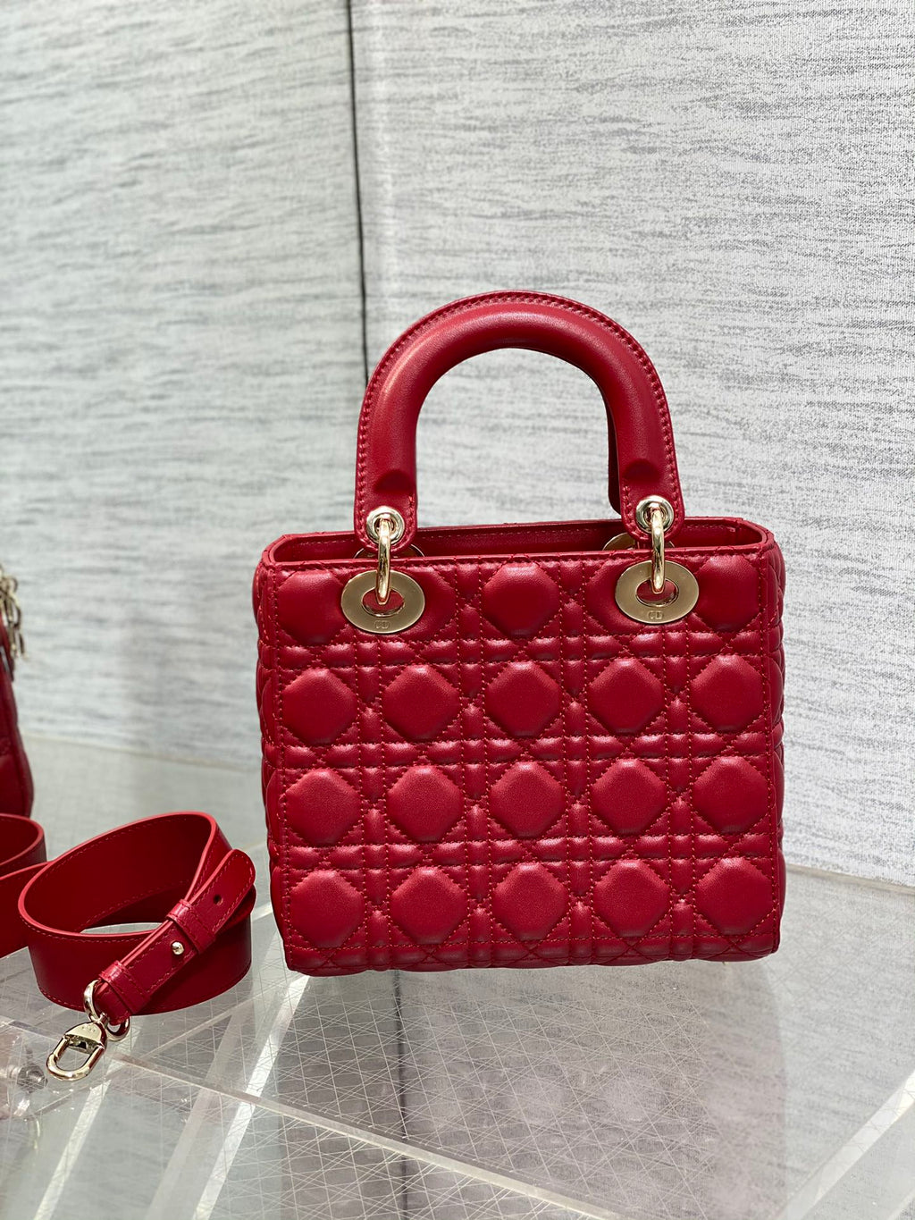 Red quilted Dior handbag with top handles and crossbody strap, gold hardware