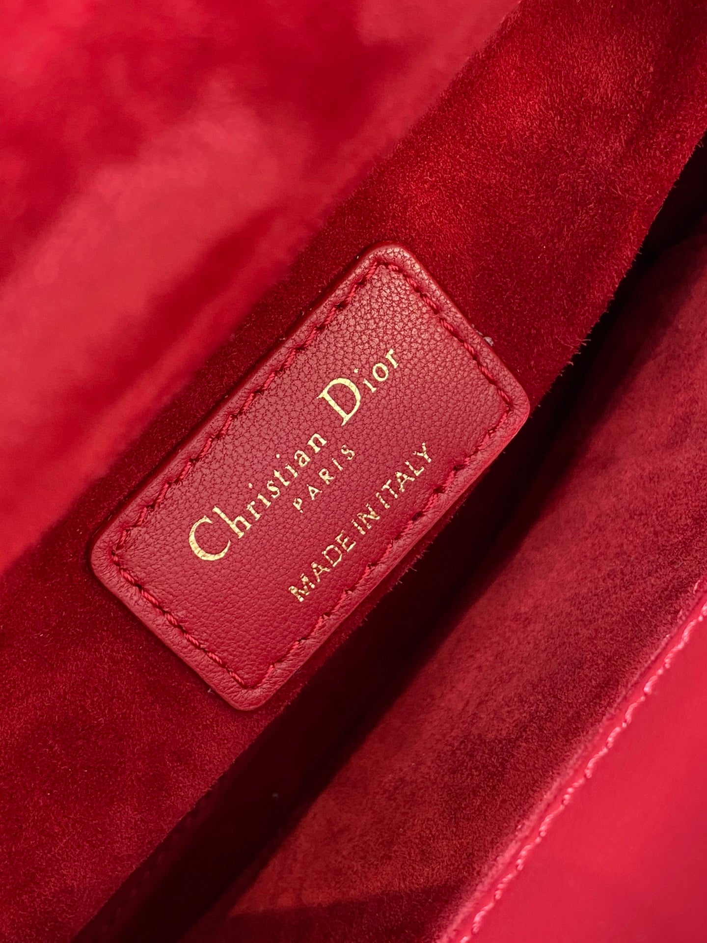 Red leather Dior label reading Christian Dior PARIS MADE IN ITALY