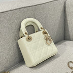 Cream quilted Dior handbag with glossy handle rings and gold charms