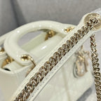 Gold chain strap on cream Dior handbag with glossy handle and hardware