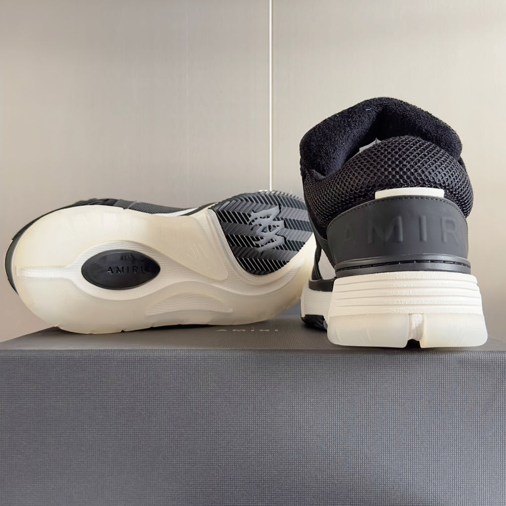 Amiri sneaker heel view with dark upper, ribbed sole tread, and logo on heel tab