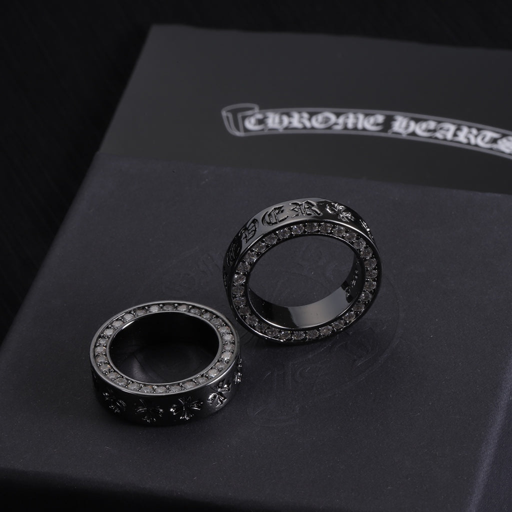Two dark-tone rings with circular crystal borders and raised engraved detailing