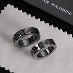Pair of silver-tone rings with engraved motifs and sparkling stone outer borders