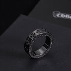 Single dark-tone ring with engraved pattern along the band and crystal trim