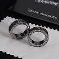 Pair of silver-tone rings with jeweled borders and engraved dark patterned edges