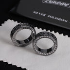 Pair of silver-tone rings with jeweled borders and engraved dark patterned edges