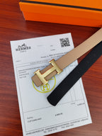 Hermes belt with light beige leather strap and gold-tone H buckle over black backing