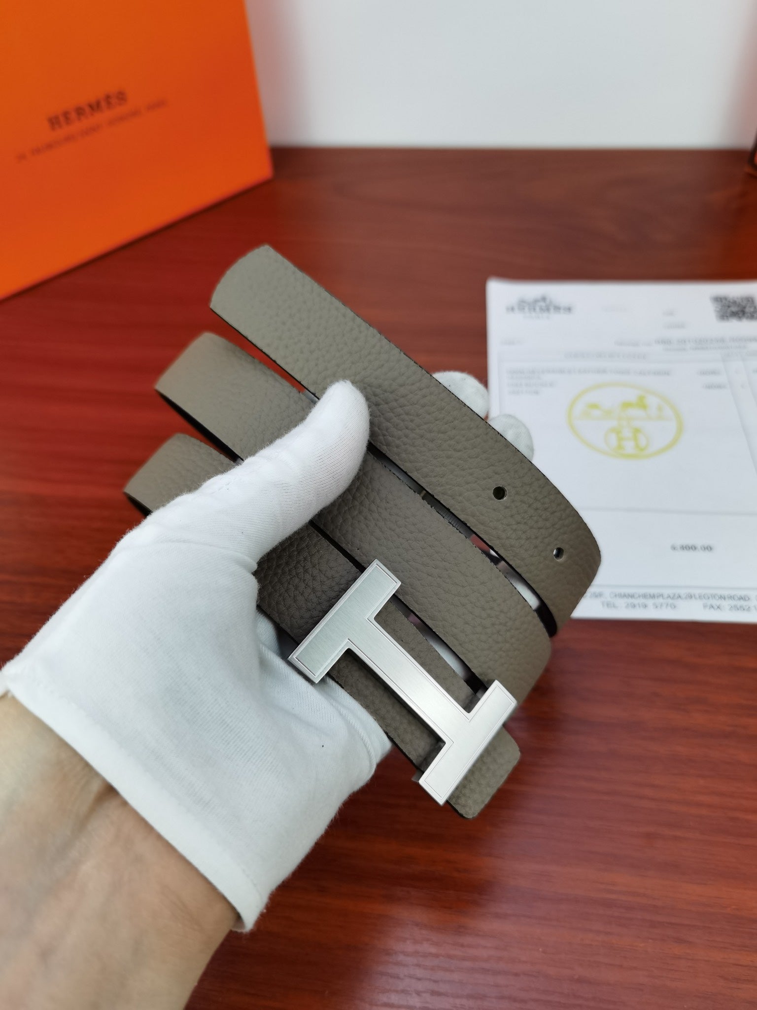 Reversible leather belt with silver-tone buckle and pin closure on light gray leather