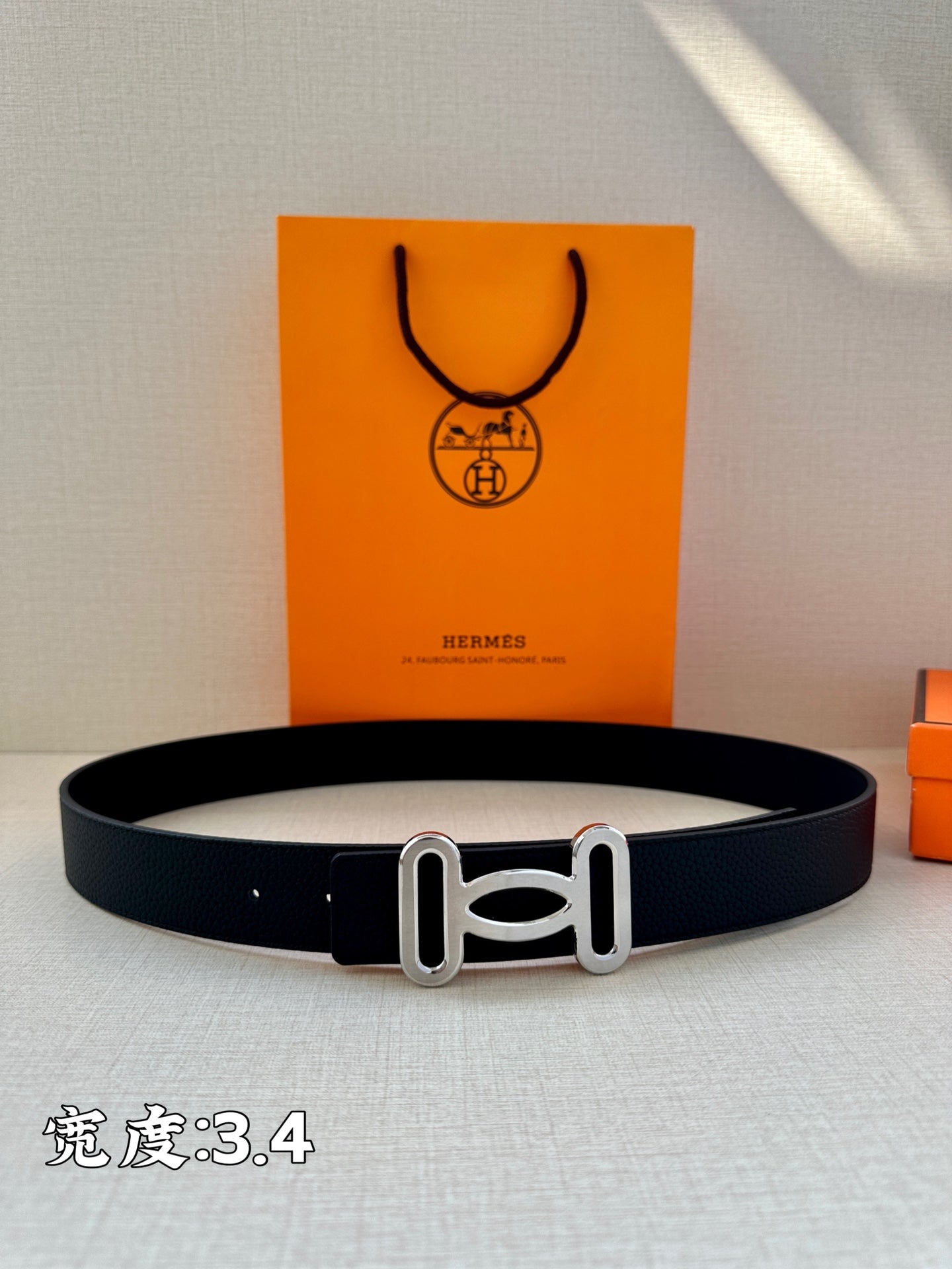 Dark leather belt with silver-toned buckle laid flat on display