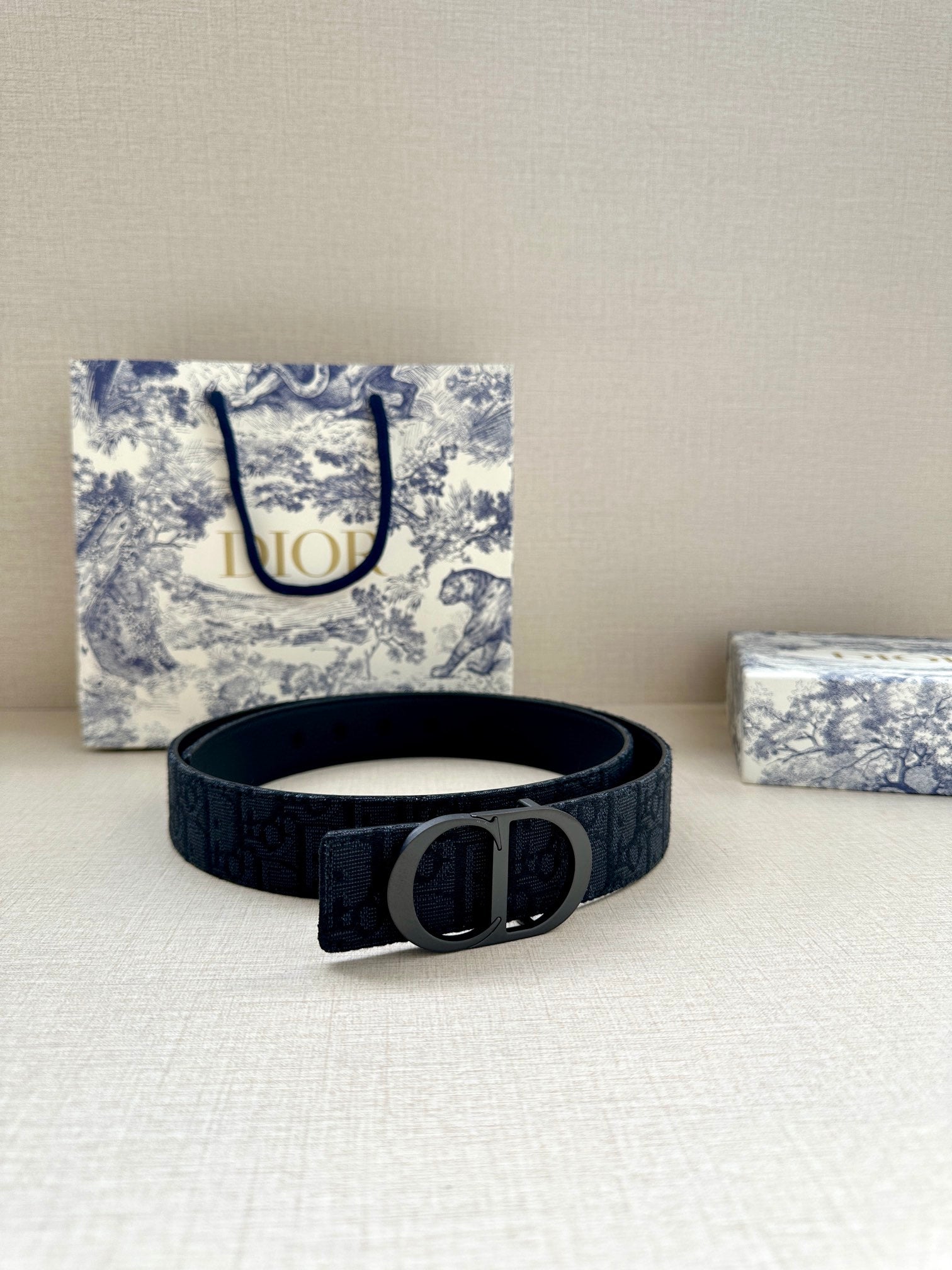 Dior belt on tabletop, dark logo strap with silver D buckle