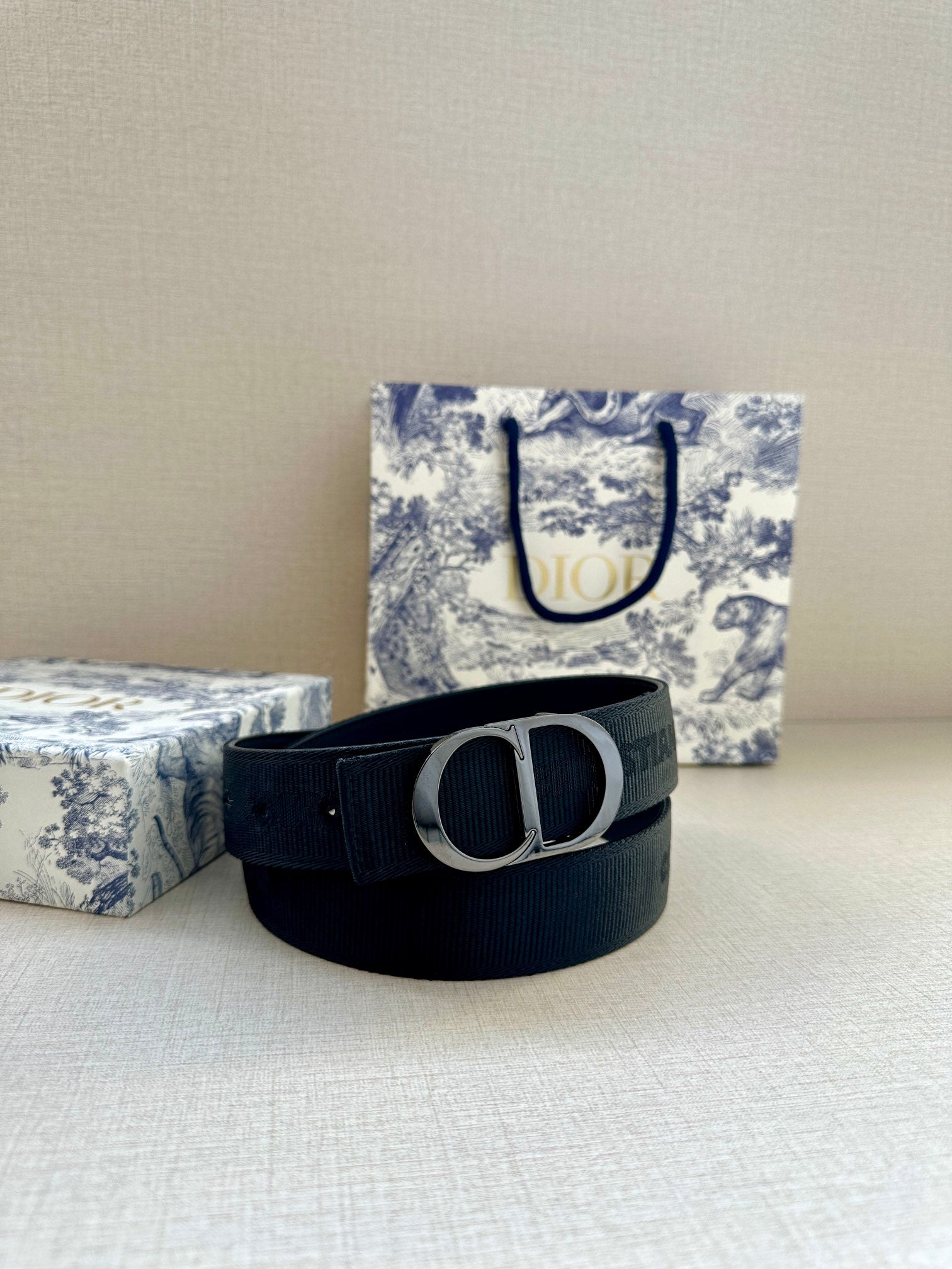 Navy fabric belt with silver-tone D buckle and embossed strap texture