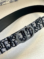 Black patterned belt strap with large round silver-tone buckle detail