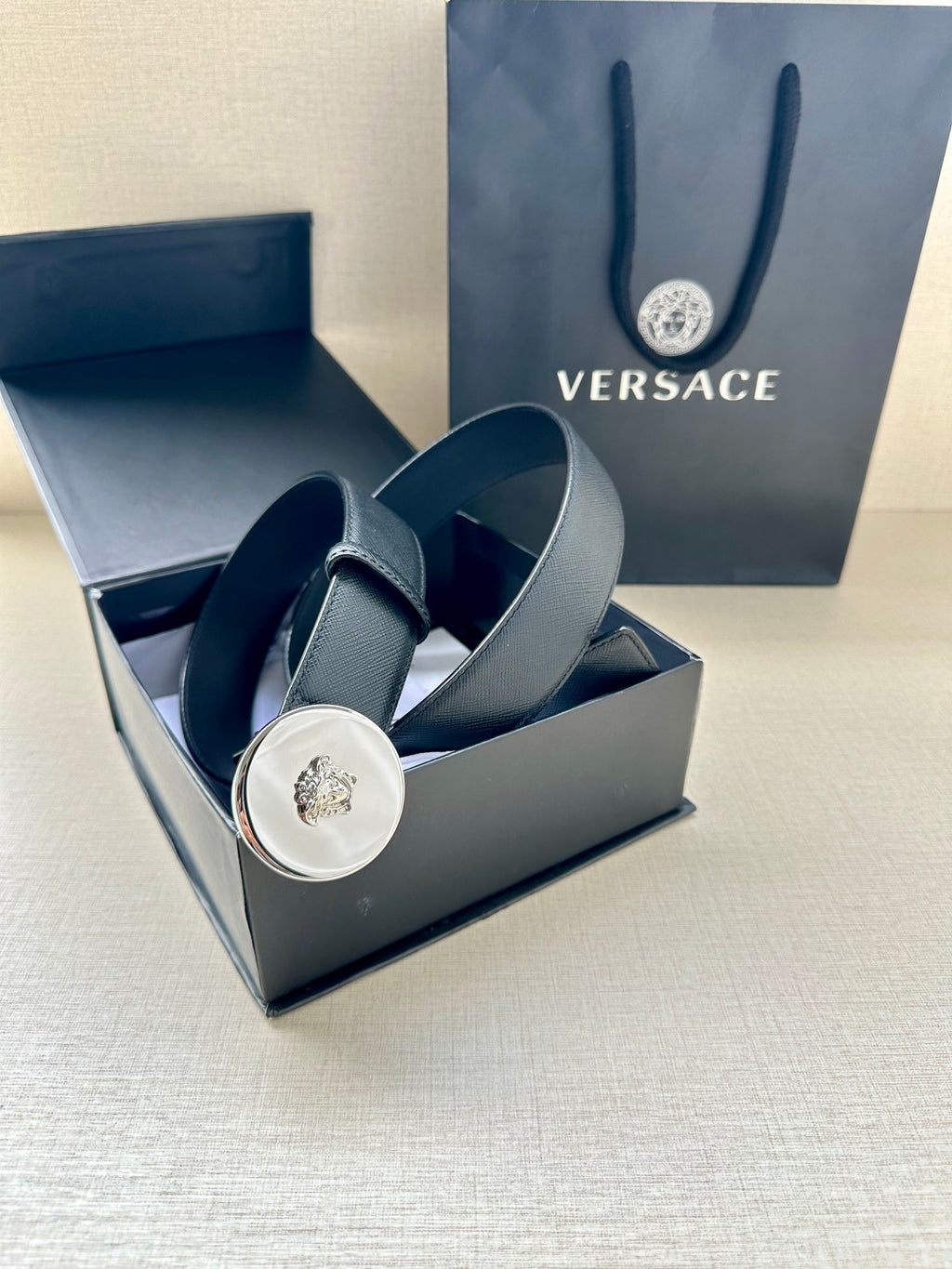 Dark blue leather belt with gold-tone round Medusa buckle displayed in a gift box.