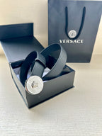 Dark blue leather belt with gold-tone round Medusa buckle displayed in a gift box.