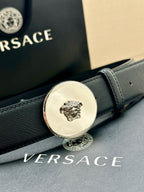 Dark blue leather belt close-up of gold-tone round Medusa buckle with engraved details.