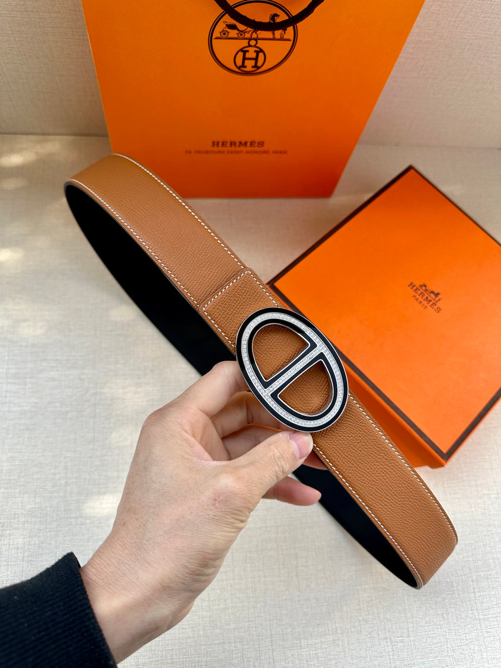 Tan leather belt with large O-shaped silver buckle and keeper strap