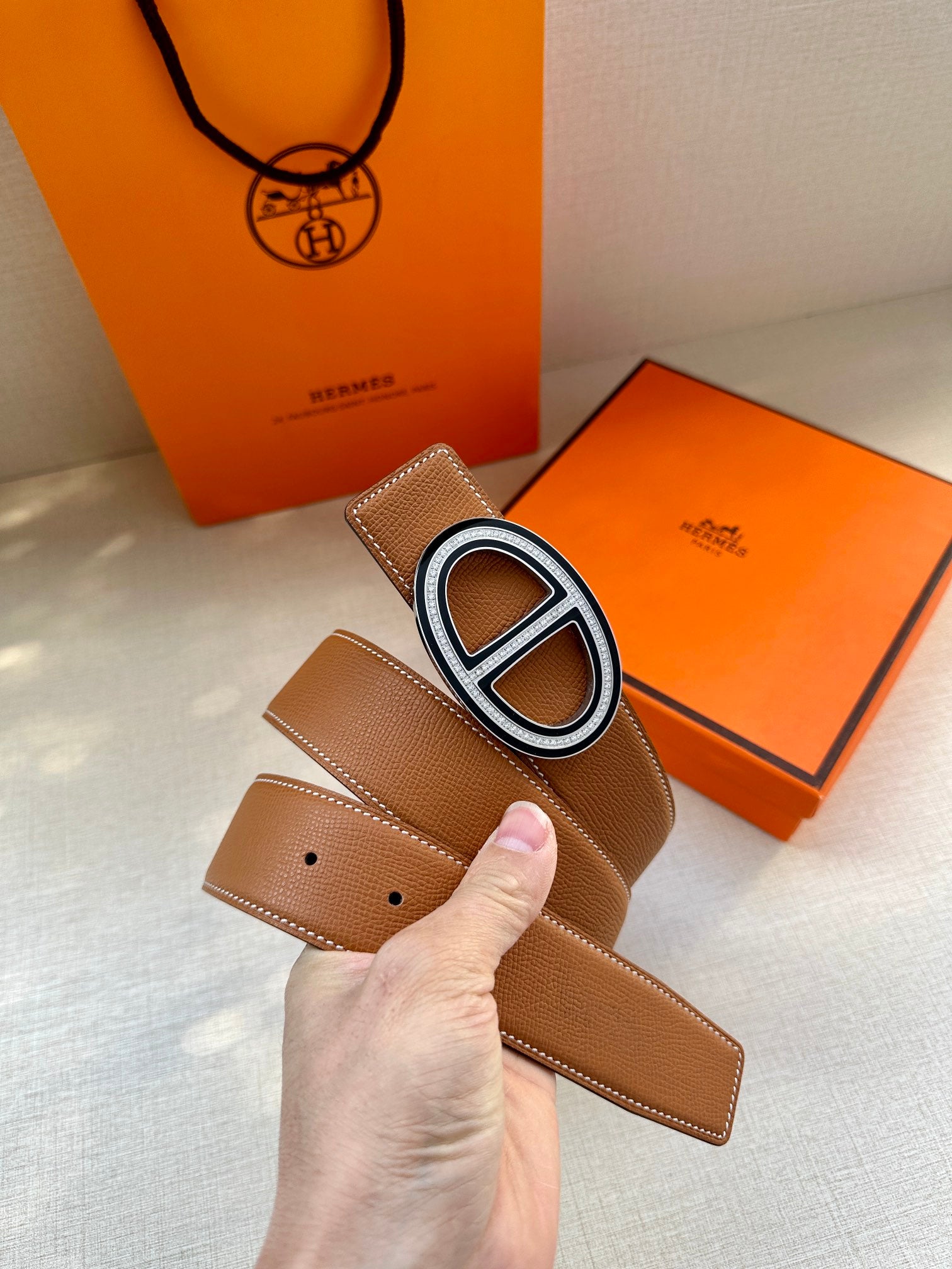 Tan leather belt with O-shaped silver buckle and punched holes end