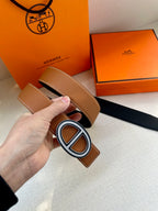 Tan leather belt with large O-shaped silver buckle and adjustable strap holes