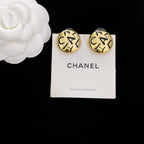 Round gold CHANEL logo stud earrings with interlocking letters on white display card