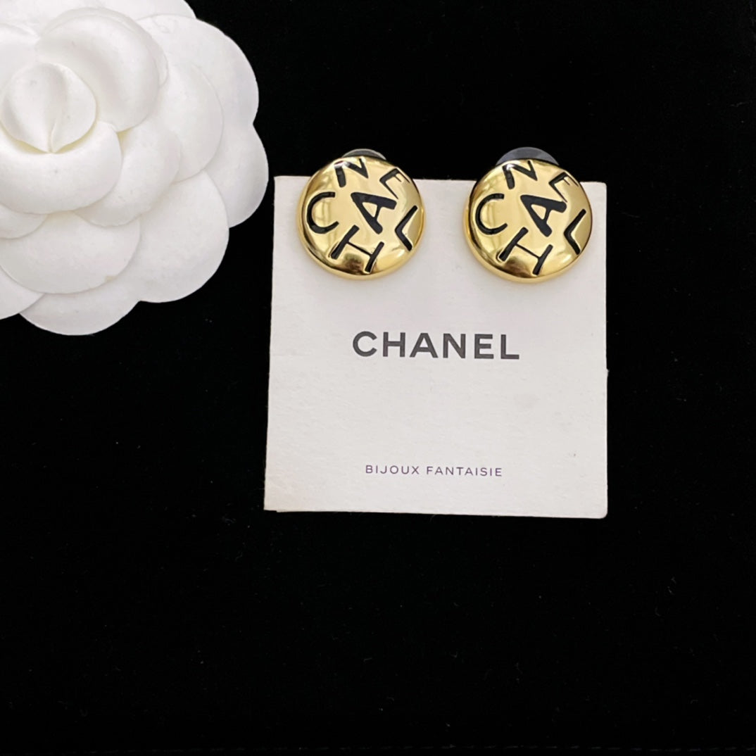 Round gold CHANEL logo stud earrings with interlocking letters on white display card