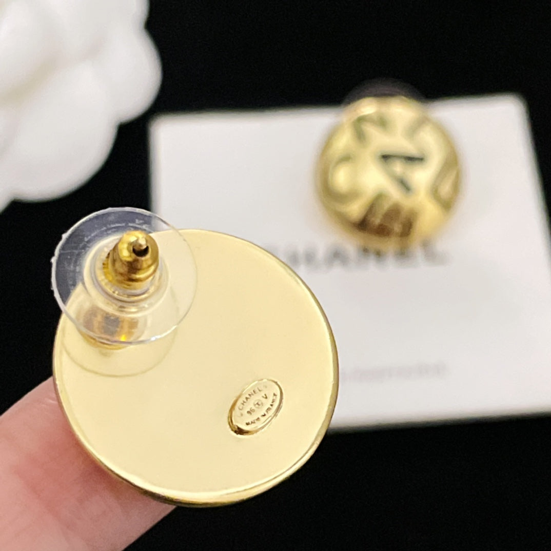 Gold CHANEL logo stud earring back with post hardware, held in hand