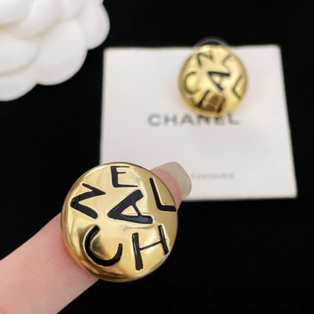 Single gold CHANEL logo stud earring with interlocking letters, held in hand