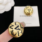 Single gold CHANEL logo stud earring with interlocking letters, held in hand