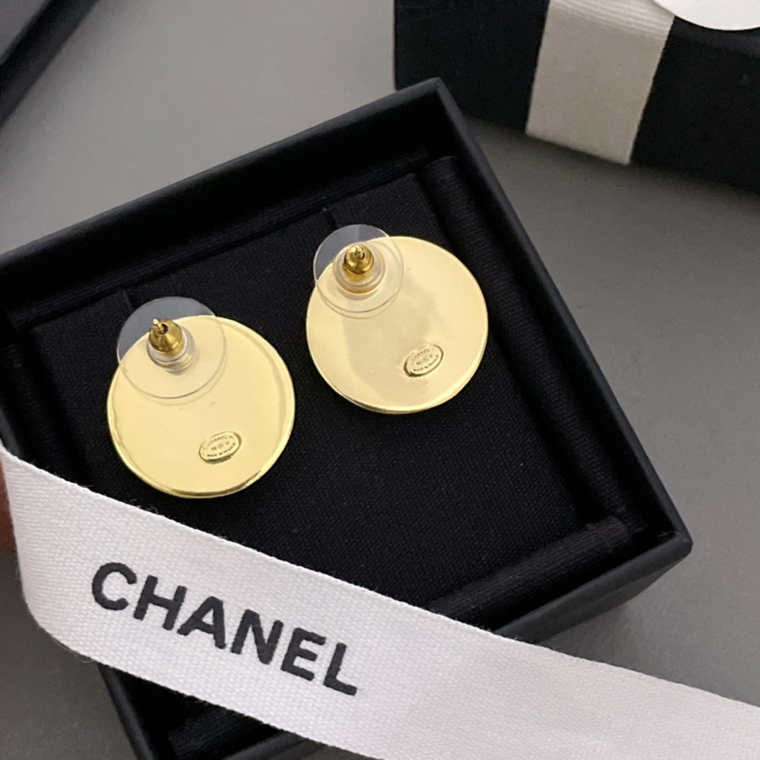 Gold CHANEL stud earrings showing backs with post hardware, in black jewelry box