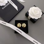 Gold CHANEL logo stud earrings with interlocking letters on a white ribbon card