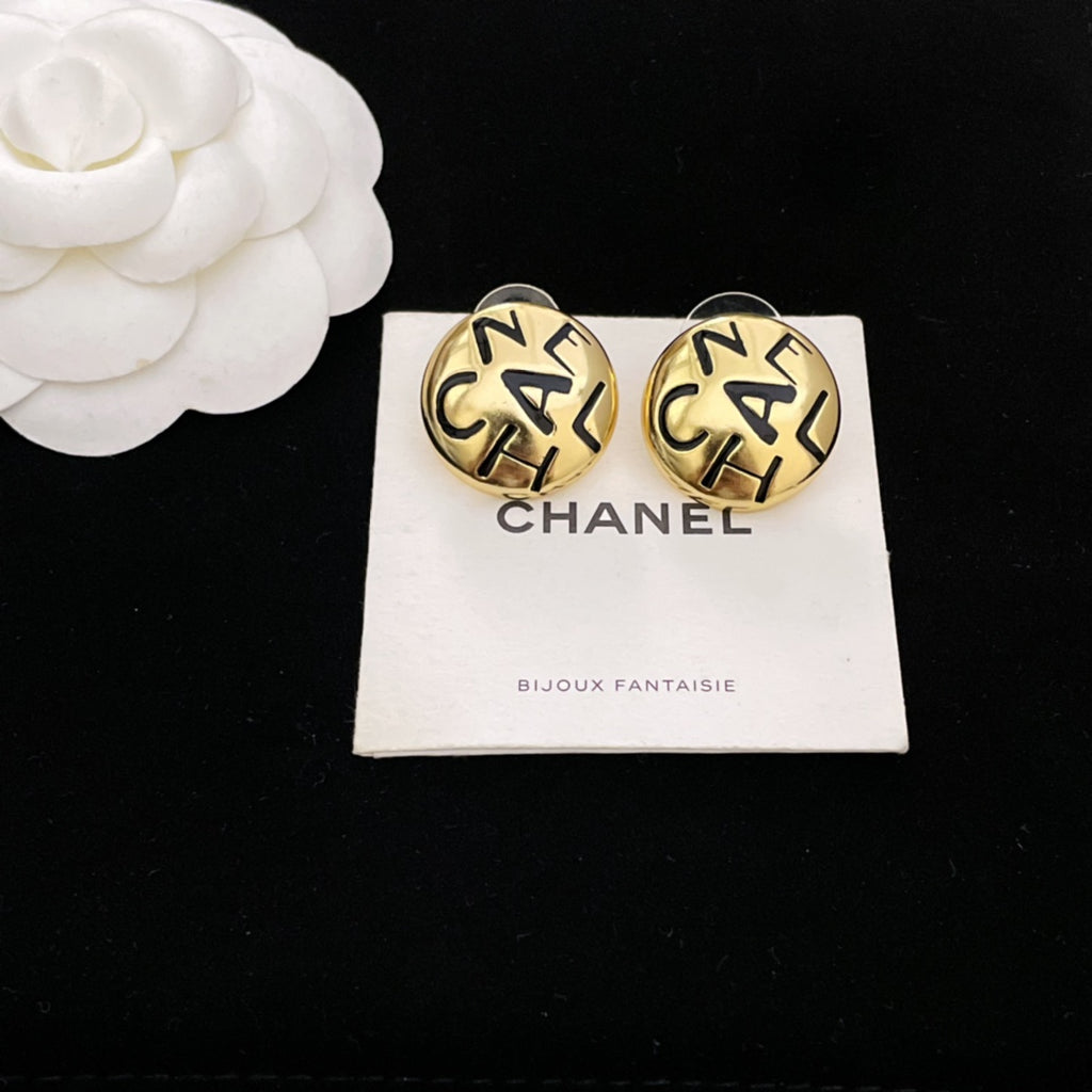 Round gold CHANEL logo stud earrings with interlocking letters, shown on white card