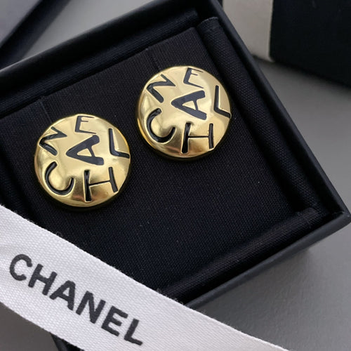 Round gold CHANEL logo stud earrings with interlocking letters, shown in black box