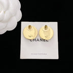 Gold CHANEL stud earrings with visible post backs on white CHANEL card