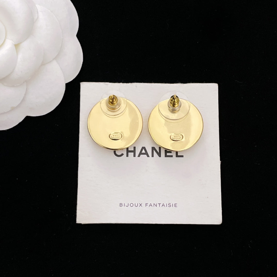 Gold CHANEL stud earrings with visible post backs on white CHANEL card