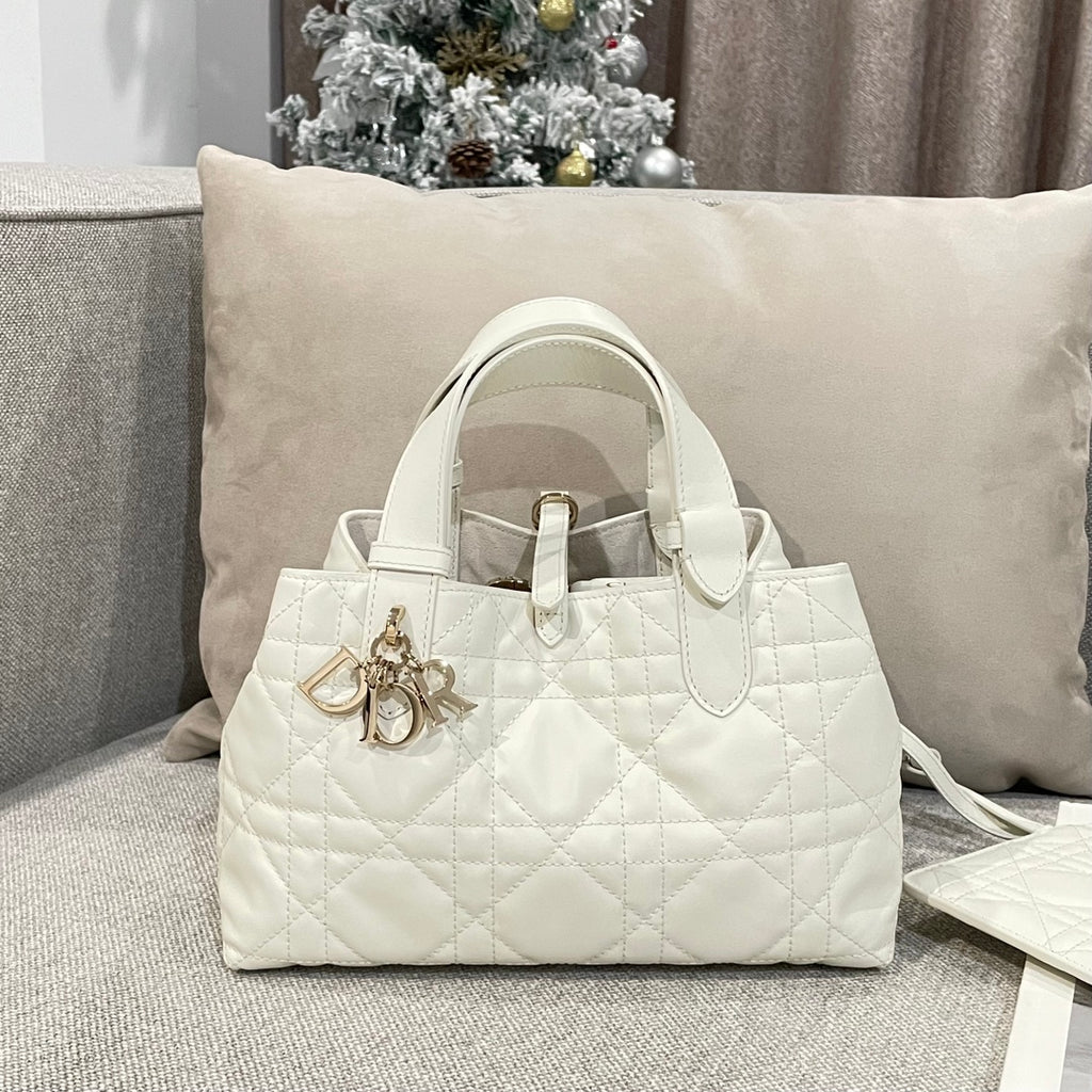 Quilted white handbag with top handles and gold logo charm