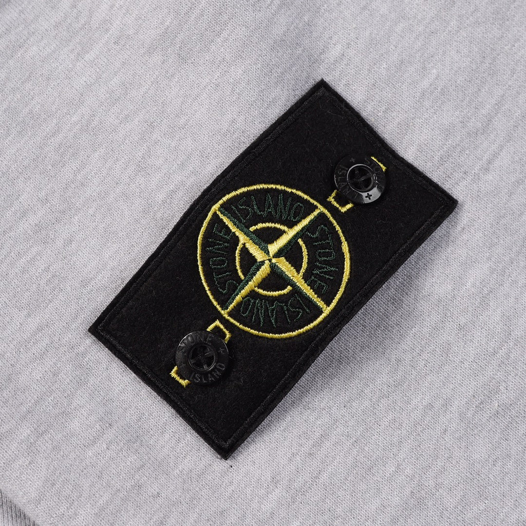 Grey sweatshirt with black logo patch featuring yellow emblem and snap buttons