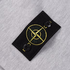 Grey sweatshirt with black logo patch featuring yellow emblem and snap buttons