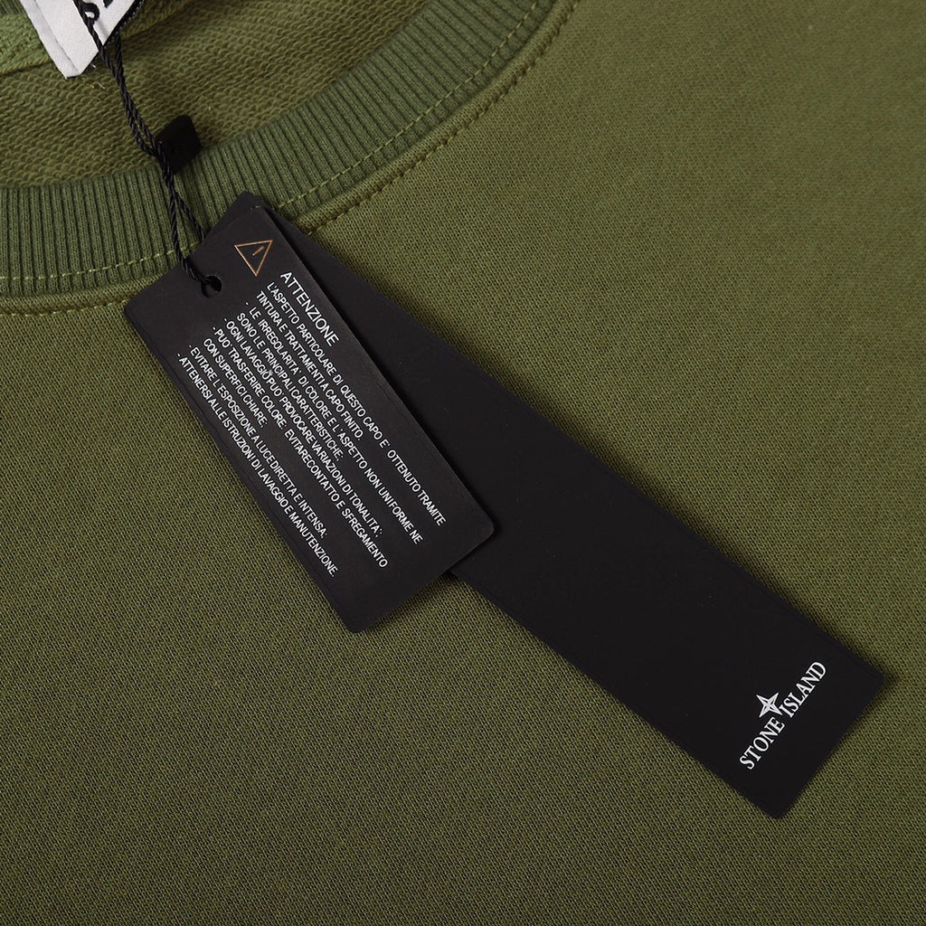 Olive green sweatshirt interior care label and size tag near neckline