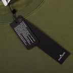 Olive green sweatshirt interior care label and size tag near neckline