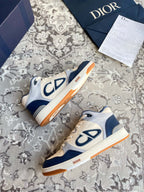 Dior unisex sneakers in cream and navy with CD logo and orange outsole trim.